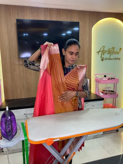 A trainer demonstrating how to hold and fold a silk saree to create the initial pleats during a professional course.