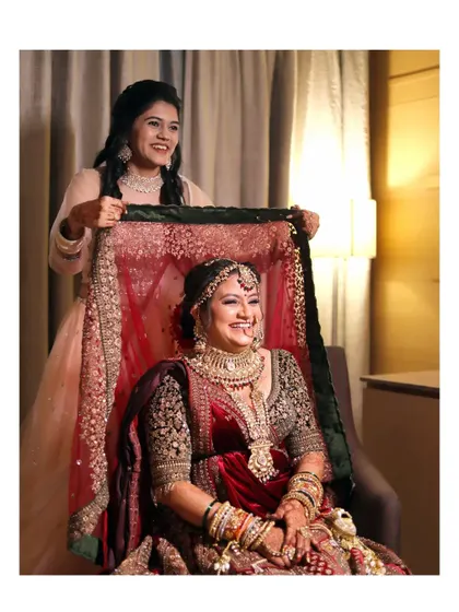 A classic shot of the bridesmaid helping the bride with her veil. The bride's radiant smile shows her happiness and excitement.