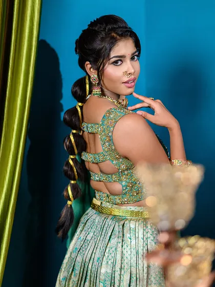 A playful yet elegant pose that gives a great view of the hairstyle and the back of the modern lehenga, showing attention to detail from all sides.