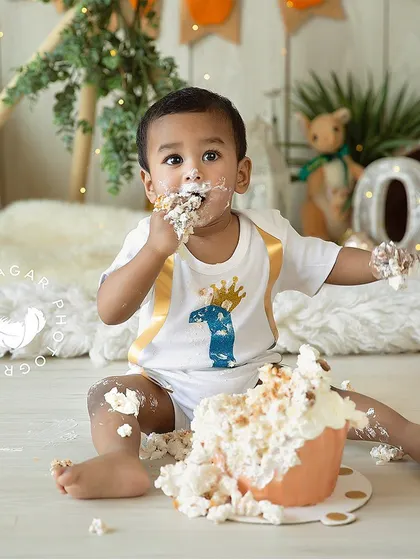 This little one is having the best time with his giant cupcake. The frosting on his face and hands is a testament to a successful and fun cake smash.