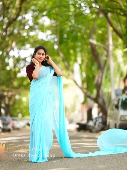 The sky-blue trail saree shown in a classic pose, with the long pallu trailing behind.