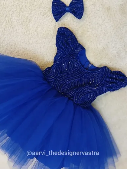The royal blue party frock with its matching hair bow. Every detail is designed to make your little one feel like a princess.