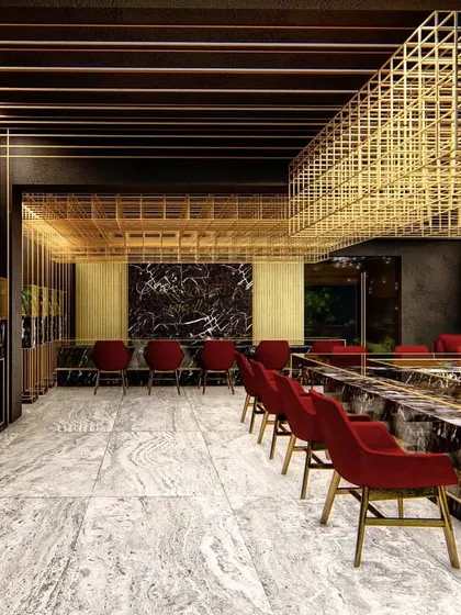 This view of the jewelry showroom highlights the interplay between the rigid brass grid, the fluid patterns of the marble, and the soft red chairs. The design creates a luxurious and immersive retail experience through a careful composition of materials.