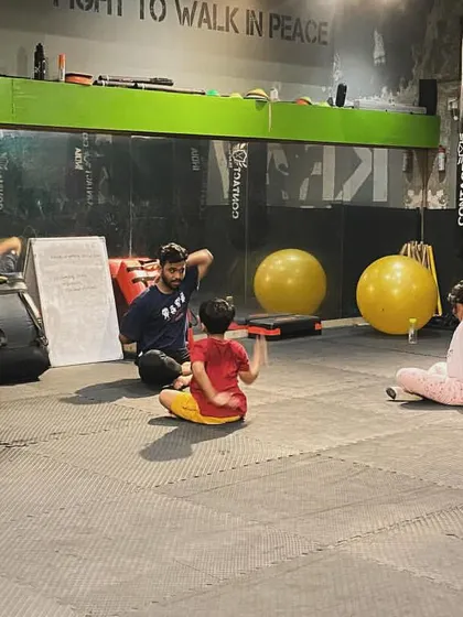 An instructor leads the kids' class in stretching exercises. Flexibility and mobility are important parts of their overall physical development.