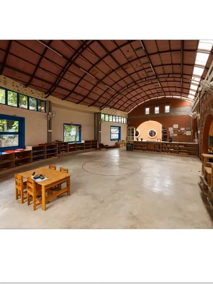 This large, multipurpose hall is defined by its high, arched roof and abundant natural light from the windows and skylights. The open floor plan provides flexibility for various activities, from group lessons to free play.