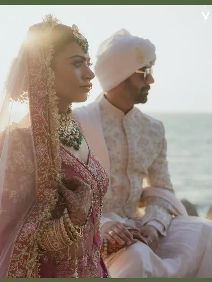 The couple sits by the sea, bathed in the golden light of the sun. This cinematic shot captures a moment of quiet reflection and togetherness against the beautiful backdrop of the ocean.
