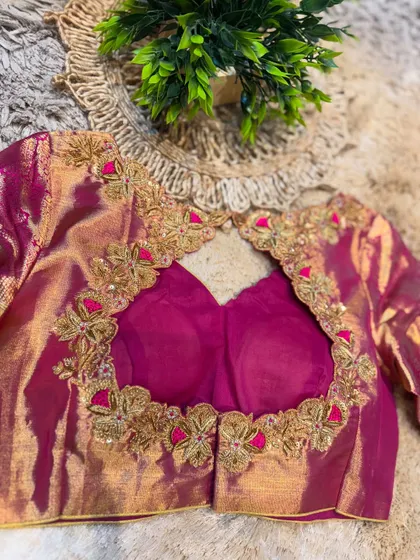 The back of a magenta blouse with an intricate cut-out design, bordered with detailed floral embroidery for a stunning rear view.