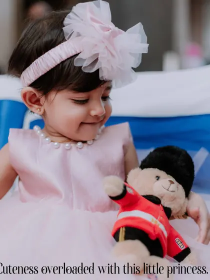 A heartwarming moment between the birthday girl and her teddy bear. This candid shot captures the innocence and sweetness of childhood during a first birthday party photoshoot.