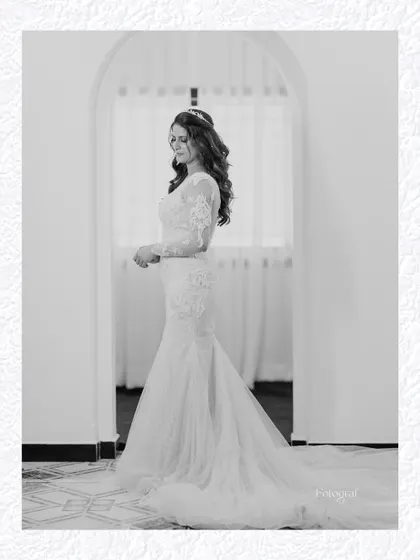 A classic, full-length black and white portrait of the bride in an arched doorway, looking elegant and timeless.