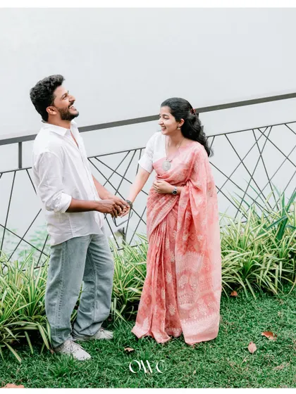 A happy, candid moment of a couple laughing and holding hands in a garden by the water.