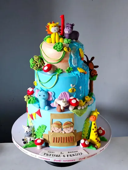 A bright and beautiful jungle safari cake for a twins' first birthday. This three-tiered masterpiece is packed with handcrafted animals, a waterfall, and two little explorers in a jeep.