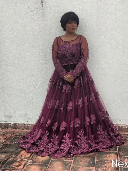 A thoughtful, standing pose against a simple white wall, letting the gown's design take center stage.