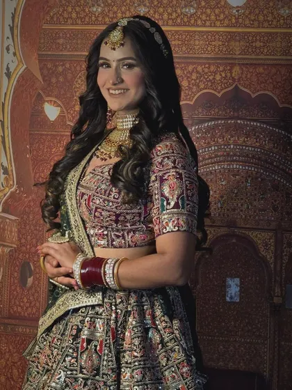 A classic bridal portrait. The bride is wearing a custom gold choker and maang tikka that perfectly complements the rich embroidery of her lehenga.