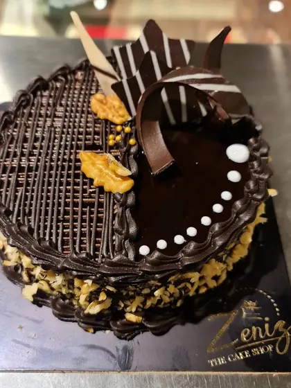 A rich chocolate walnut cake with intricate chocolate work on top. The combination of dark chocolate and crunchy walnuts is a timeless favorite.