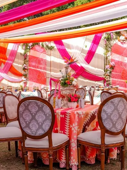A view of the dining area at the vibrant Mehendi, with tables dressed in colorful printed cloths and surrounded by elegant chairs.