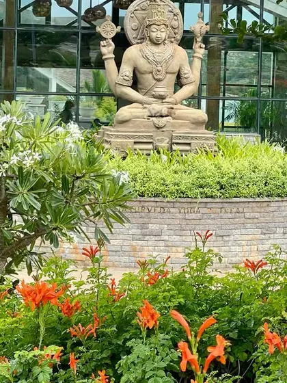 The Lord Dhanvantari statue framed by blooming orange flowers. This image beautifully merges the spiritual and natural elements that define our retreat.