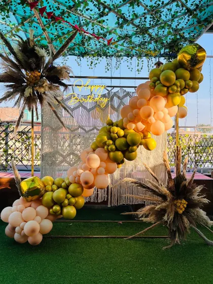 A beautiful boho-style balloon arrangement on a terrace, with pampas grass and a macrame backdrop.