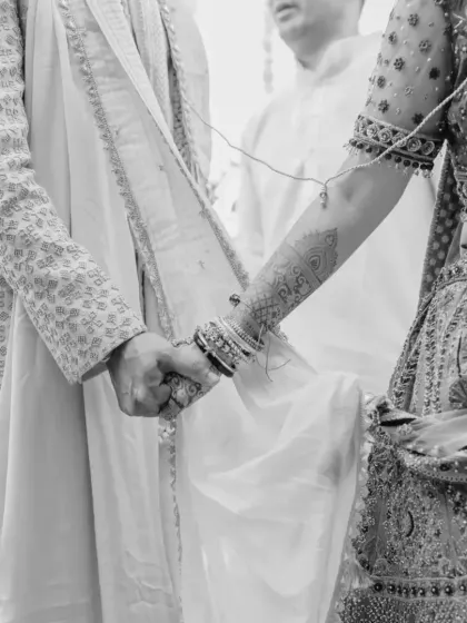 A black and white shot of the couple holding hands during the 'pheras', a classic symbol of their lifelong bond.