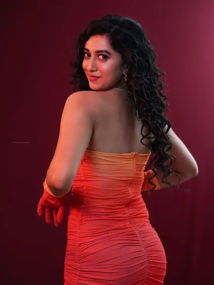 A back view of the model, showing off her curly hair and the design of the dress.
