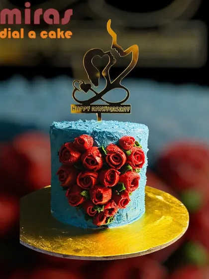 A passionate and romantic anniversary cake. The small blue cake is adorned with a heart made of rich red buttercream roses and a "Happy Anniversary" topper.