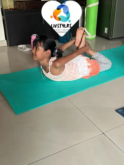A young girl in Dhanurasana (Bow Pose), smiling as she stretches. My kids' yoga classes are all about finding joy in movement.