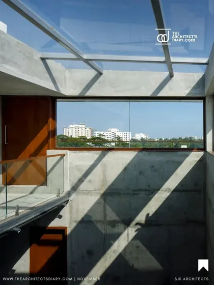 A glass skylight floods the central atrium of the apartment building with natural light, which cascades down the exposed concrete walls, creating dramatic shadows and illuminating the common areas.