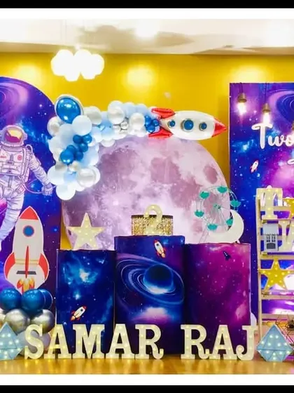 Samar's "Two the Moon" second birthday was an out-of-this-world space mission. The setup includes a large moon backdrop, astronaut and rocket cutouts, and galaxy-themed pedestals for a cosmic celebration.