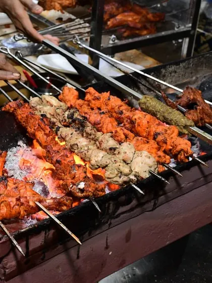 Our tandoor grill in full swing, with various chicken tikkas and seekh kebabs being cooked over hot coals for that authentic smoky flavor.