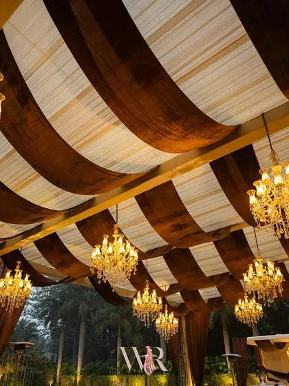 A view of the striped ceiling and the forest of chandeliers. The contrast between the dark brown velvet and the white fabric, combined with the warm light, created a dramatic and luxurious effect.