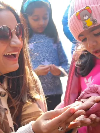 A mother and child share a moment of discovery, looking at an earthworm. Even during a party, there are opportunities for learning and connecting with nature.