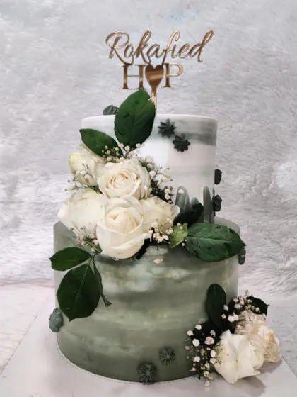 A beautiful two-tiered cake to celebrate a 'Rokafied' engagement. The sage green watercolor effect and fresh white roses create a sophisticated and modern look for this special pre-wedding ceremony.