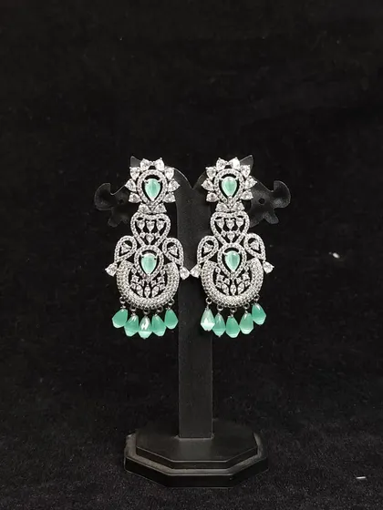 A pair of modern, silver-finish earrings with mint green stones. Perfect to rent for a cocktail party.