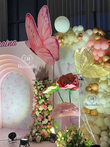 A detailed shot of the main stage, focusing on the right side with its mix of gold and white balloons, giant flowers, and a golden butterfly prop.