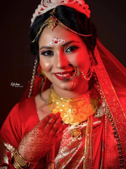 A warm and inviting portrait of the Bengali bride. The red lighting complements her traditional attire, and her gentle smile makes for a beautiful, classic shot.