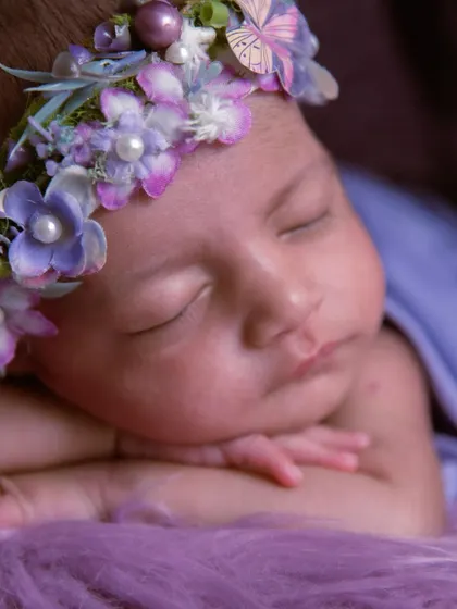 A close-up on pure innocence. The detail in the floral and butterfly headband is exquisite, perfectly complementing the baby's delicate features.