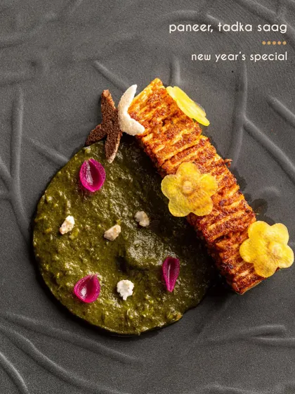 A modern interpretation of a winter classic, paneer with tadka saag. The paneer is scored and grilled, served alongside a creamy spinach puree and garnished with delicate edible flowers.