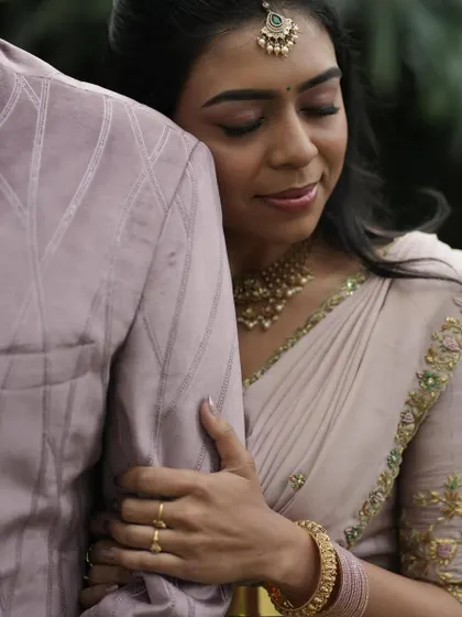A tender moment between the couple, her hand resting on his arm, showcasing the sleeve embroidery.