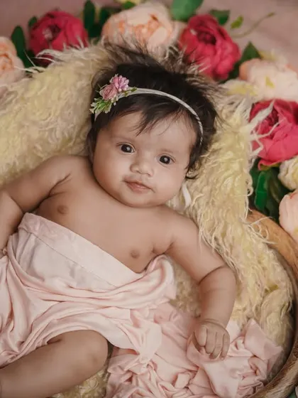 A floral beauty. This older baby is awake and alert, her bright eyes shining as she lies in a bed of flowers.