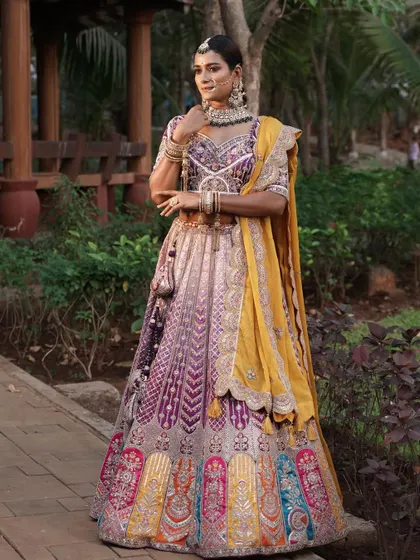 A full-length shot of the model in the multi-color lehenga in an outdoor setting.
