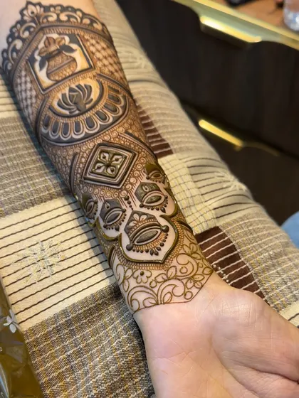 The finished arm band, a masterpiece of intricate patterns. It features a 'kalash', lotus, geometric shapes, and delicate hanging elements, all tied together with a fine leafy border.