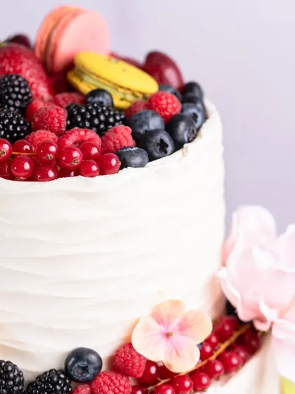 Another detail shot of the two-tiered cake, highlighting the textured buttercream and fresh floral accents.