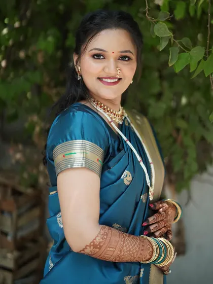 A beautiful portrait of bride Shivali. Her makeup is soft and glowing, perfectly suited for her teal blue silk saree and the daytime engagement ceremony.