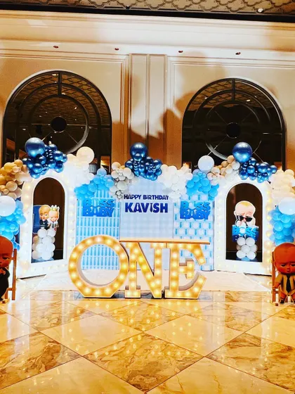 The main stage for the "Boss Baby" birthday, featuring a city skyline backdrop, balloon arches, and large "ONE" marquee letters.