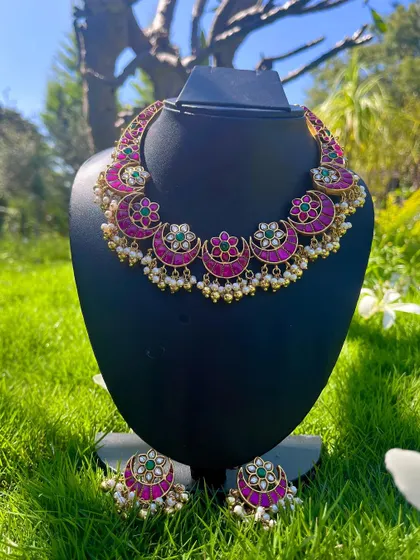 This is a classic Kemp choker with a chandbali design, featuring bright pink stones and green accents. It comes with matching earrings and is perfect for traditional events.