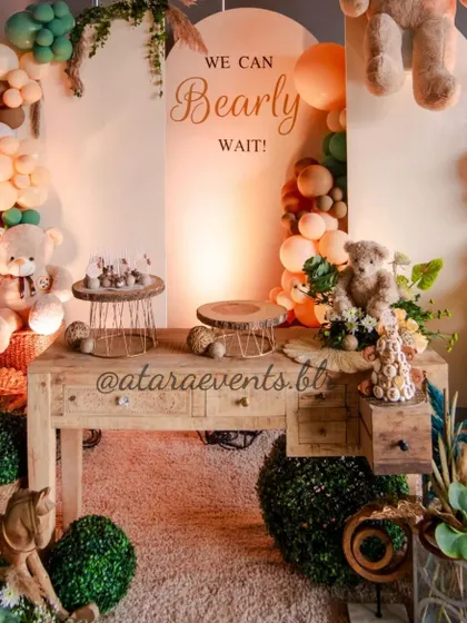 A dessert table setup for a "We Can Bearly Wait" baby shower. The rustic wooden table is adorned with teddy bears, balloons, and sweet treats, creating a charming and cohesive look.