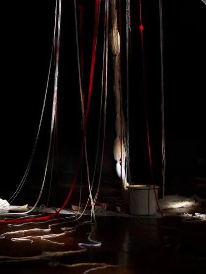 A look at the stage setup for "Medea," where hanging threads and a single bucket create a powerful and desolate atmosphere for the Greek tragedy.
