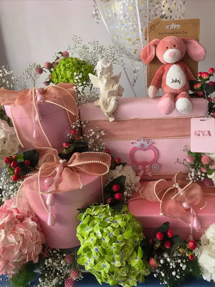 A close-up of the pink floral hamper, showing the mix of flowers and gift boxes.