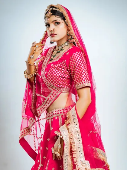 This shot captures the elegance of the bride adjusting her veil, with the focus on the beautiful hand jewellery and blouse details.