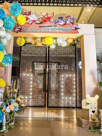 Another view of the party entrance, showcasing the balloon arch, themed signage, and a welcoming Pooh Bear cutout.