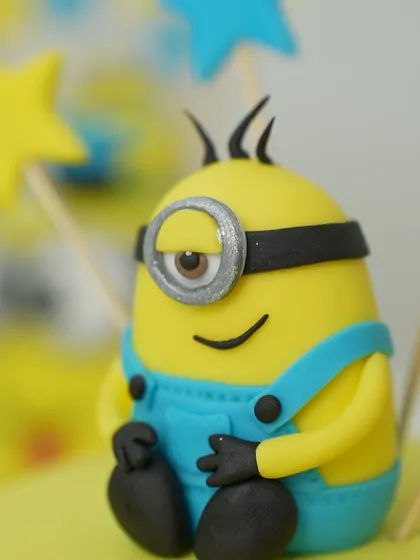 A close-up of a fondant Minion topper, crafted by a student. We teach you how to model figurines with personality, paying attention to details like the expression and texture.